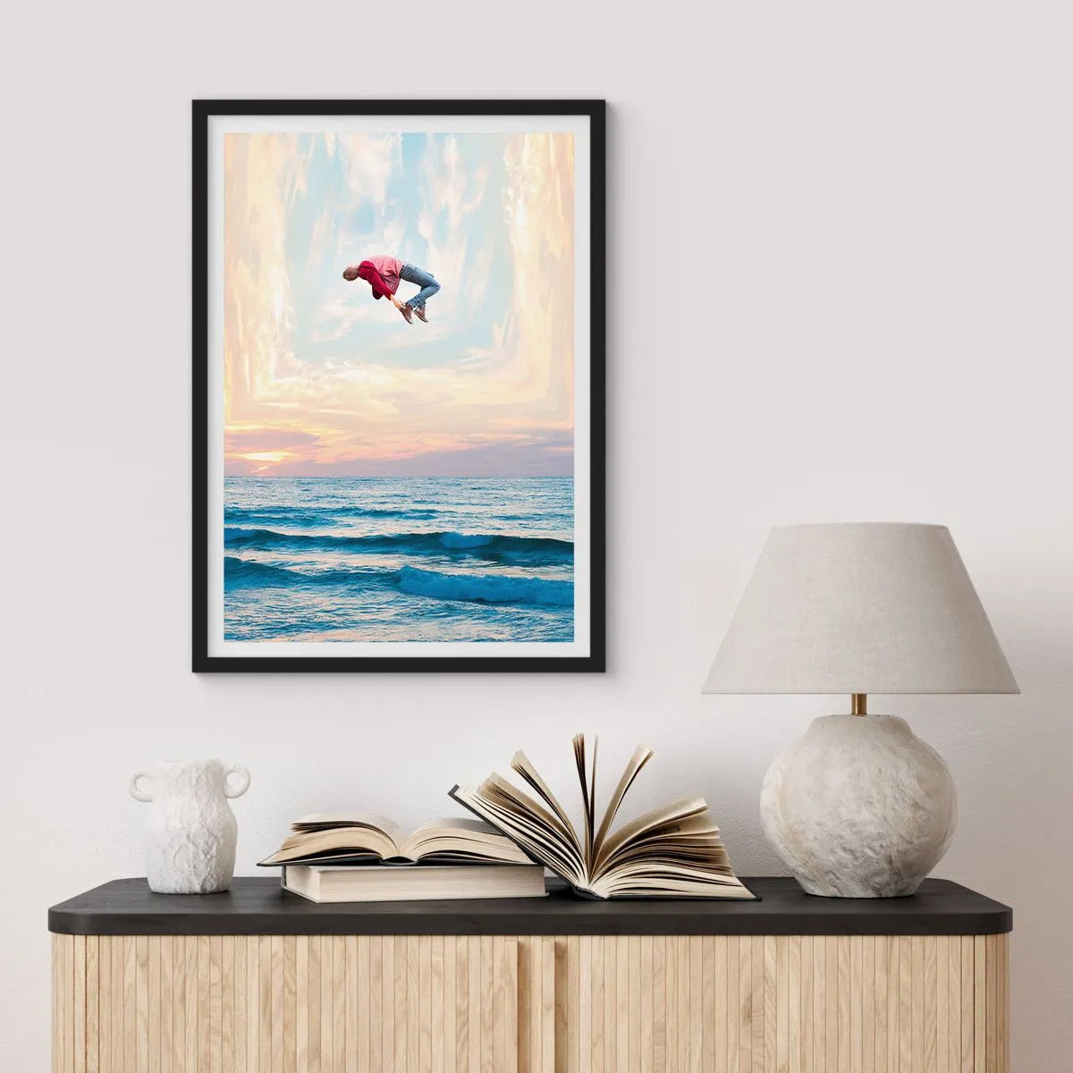 Poszter fehér keretben - Egy férfi naplementekor az óceán felett az égbe ugrik - 50x70cm - Egy másik dimenzióba - Modern fali dekoráció nappalihoz és hálószobához ARTTOR